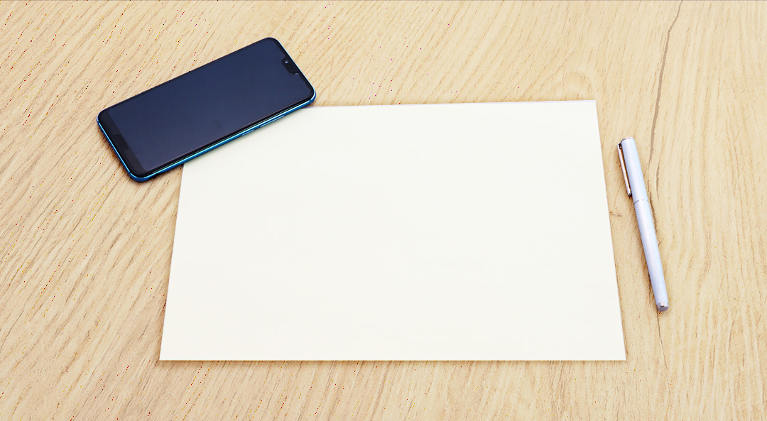 Foto eines leeren Blatts Papier, auf dem ein Smartphone mit leerem Display liegt