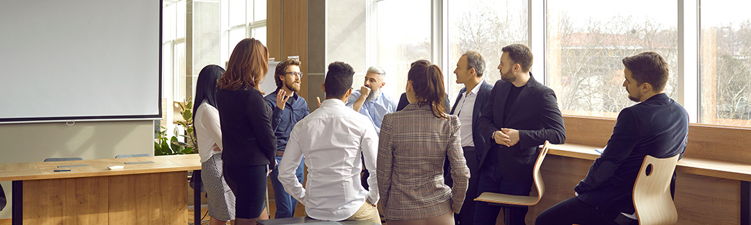 Eine Gruppe von Personen diskutiert stehend in einem Besprechungsraum.