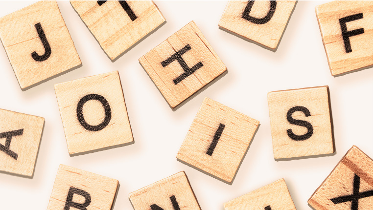 Foto von durcheinander liegenden Scrabble-Spielsteinen mit Buchstaben, die kein Wort bilden.